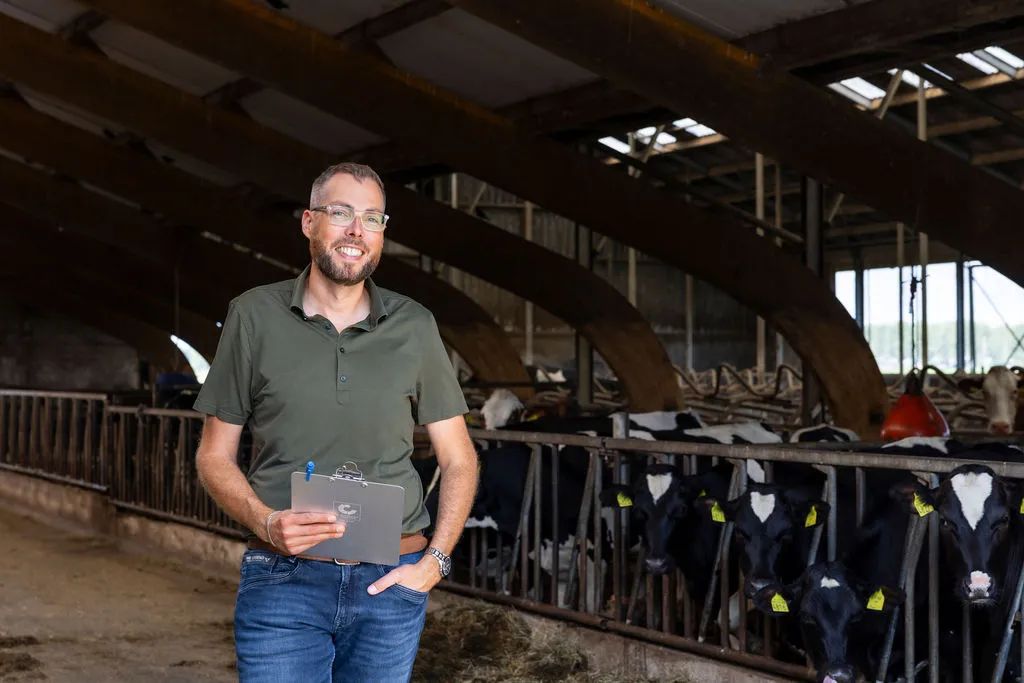 Jan Jelle met auditdocumenten in een melkveestal